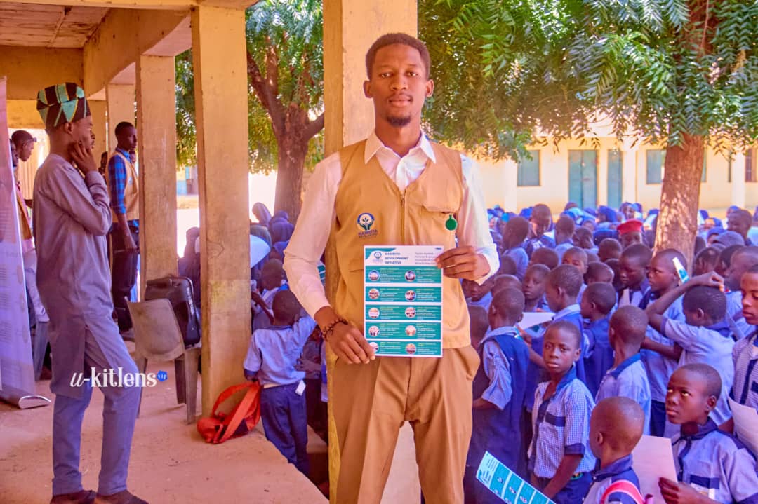 Large crowd of students holding KDI malaria prevention leaflets outside school